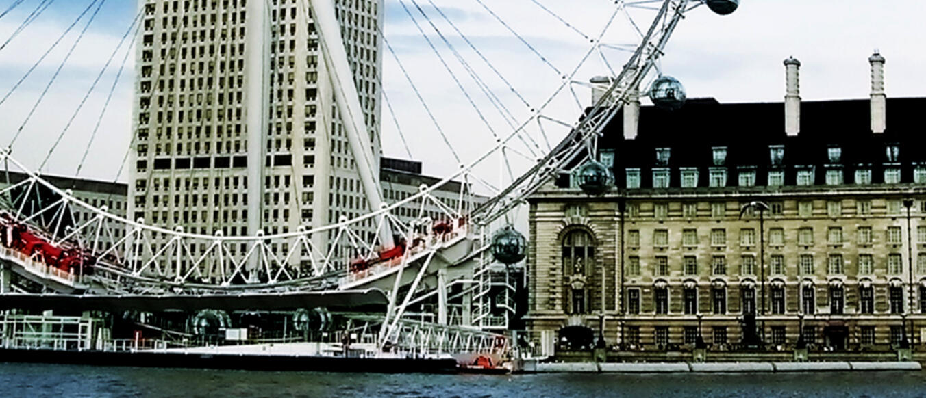 The ferris wheel next to a building on the river