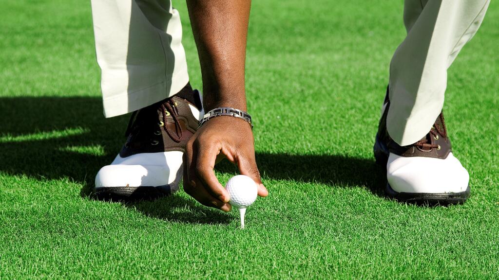hand placing golf ball on tee